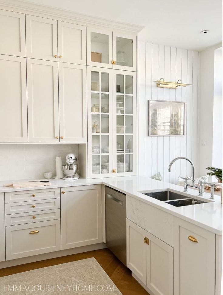 a kitchen with white cabinets and gold handles on the sink, dishwasher and oven