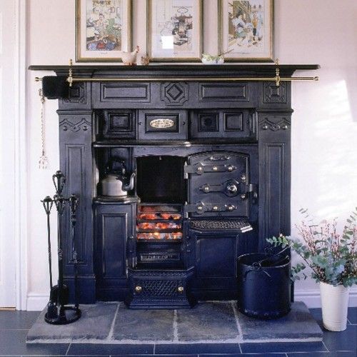 an old fashioned stove in the middle of a room with pictures on the wall above it