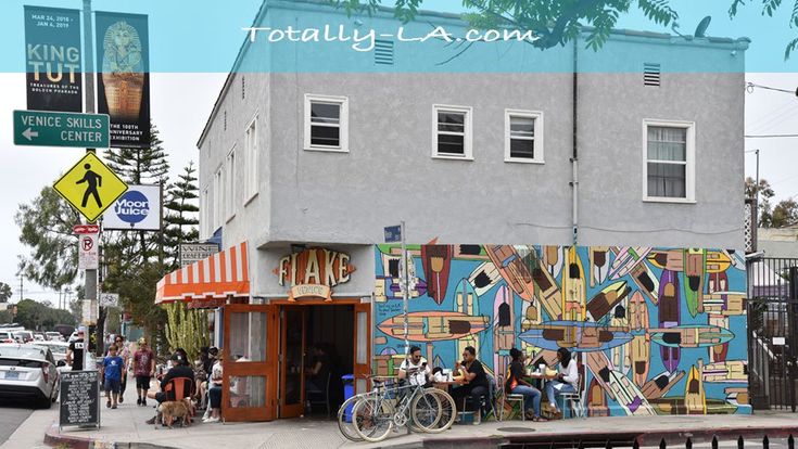 people are standing on the sidewalk in front of a building that has been painted with colorful images