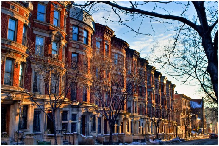 a row of brick buildings with trees in the foreground and snow on the ground