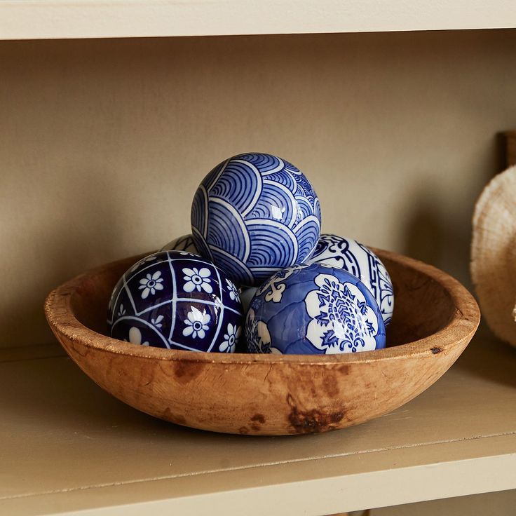 several blue and white vases in a wooden bowl on a shelf next to a teddy bear