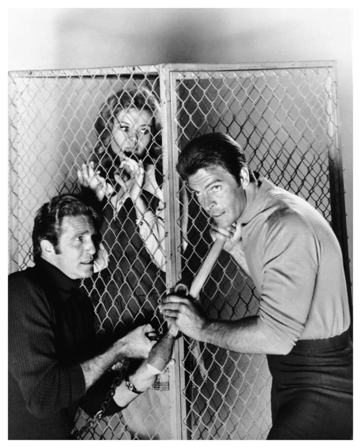 two men are holding baseball bats in front of a chain link fence while another man looks on