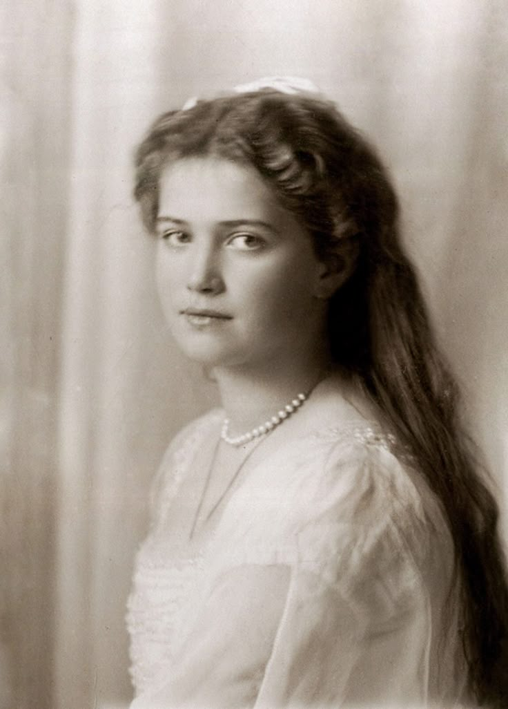 an old black and white photo of a woman with long hair wearing a pearl necklace