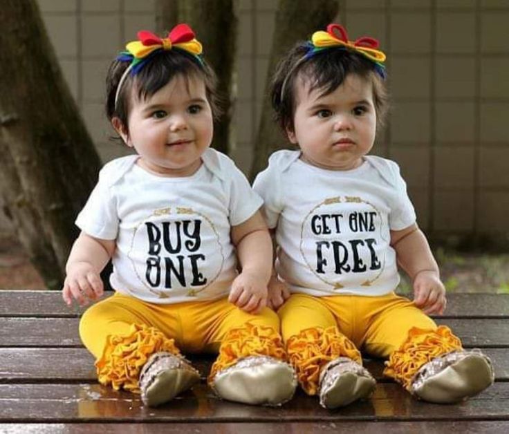 two toddlers sitting on a wooden bench wearing t - shirts with the words buy one get one free