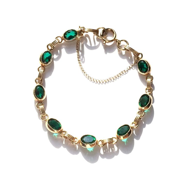 Captivating 1960s vintage gold filled bracelet has beautiful simulated emeralds! The color is a deep green with faint blue undertones, and makes this dainty 12K gold filled bracelet a perfect jewelry gift.  Eight oval faceted glass stones are set in gold filled bezels. 12K gold filled settings and links close with a spring ring clasp and comes with a safety chain. This green stone bracelet along with all our high quality gold filled, vintage jewelry of the past century will mix seamlessly with a Green Oval Bracelets For Anniversary, Green Retro Jewelry For Anniversary, Vintage Oval Gold Bracelet For Formal Occasions, Vintage Oval Bracelets For Anniversary, Retro Green Jewelry For Anniversary, Vintage Oval Gold Bracelet As Gift, Vintage Oval Gold Bracelet For Gifts, Green Oval Link Classic Jewelry, Vintage Oval Jewelry For May Birthstone