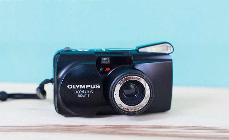 a camera sitting on top of a wooden table next to a blue wall and a black cord