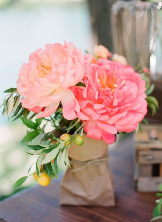 a vase filled with pink flowers sitting on top of a wooden table