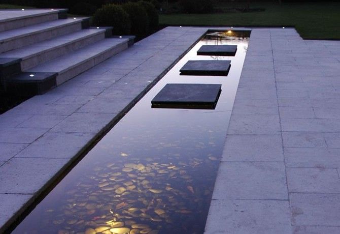 an empty pool with steps leading up to it and lights shining on the water below