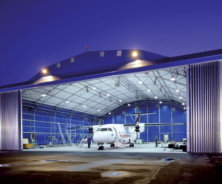 an airplane is parked in the hangar with lights on it's sides and doors open