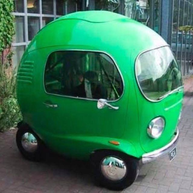 a small green car is parked on the side of the street