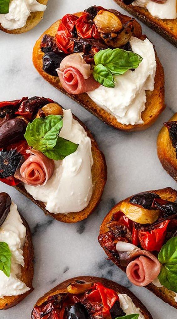 several pieces of bread with various toppings on them sitting on a marble counter top