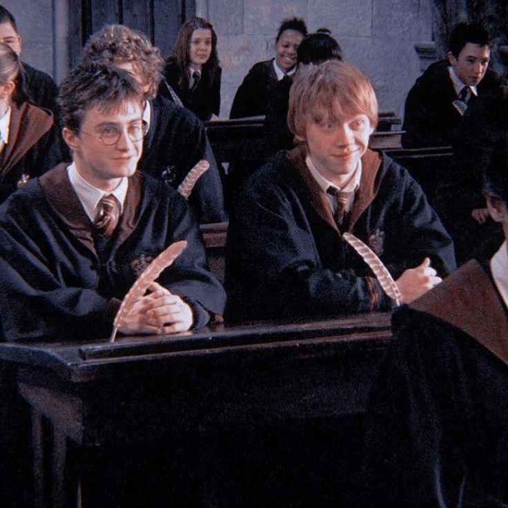 harry potters sitting at their desk in front of other students and one is holding a banana