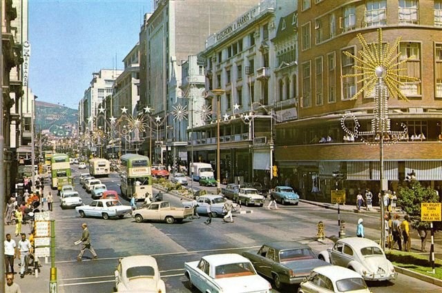 an old photo of cars and people on the street