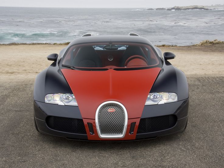 a red and black bugatti is parked on the beach next to the ocean