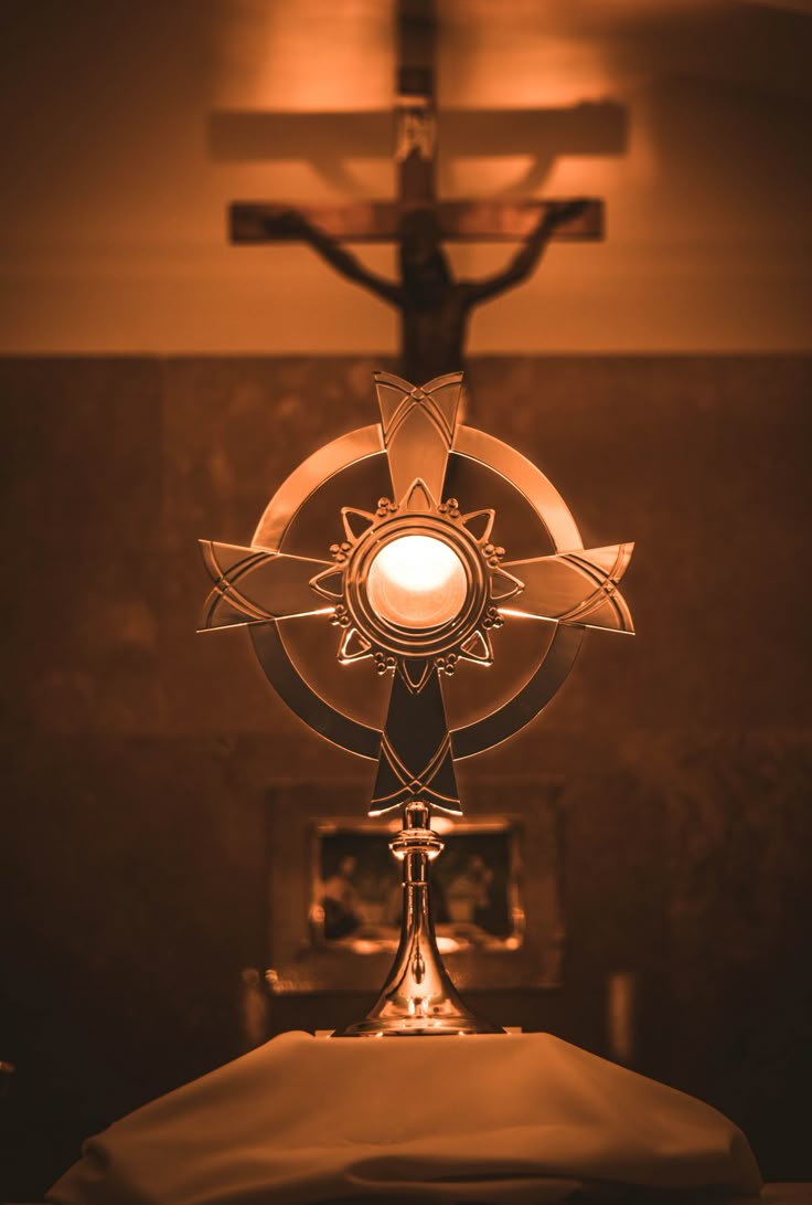 the cross is lit up with a candle in front of it on top of a bed