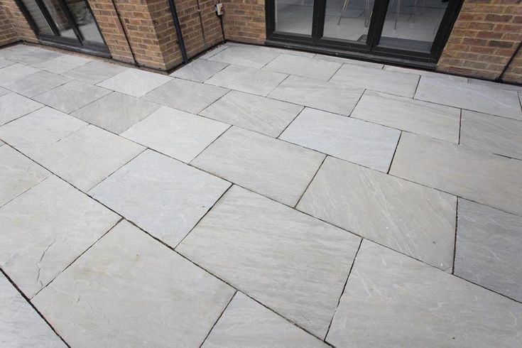 an outdoor patio with stone pavers and glass doors