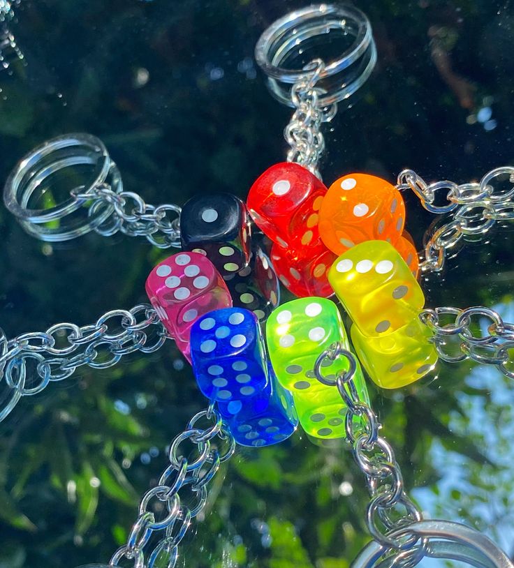 four colorful dices hanging from chains in front of a tree