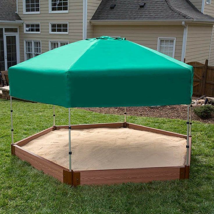 a large green umbrella sitting on top of a wooden platform in the middle of a yard