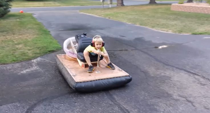 a little boy is playing on an inflatable boat that's floating down the street