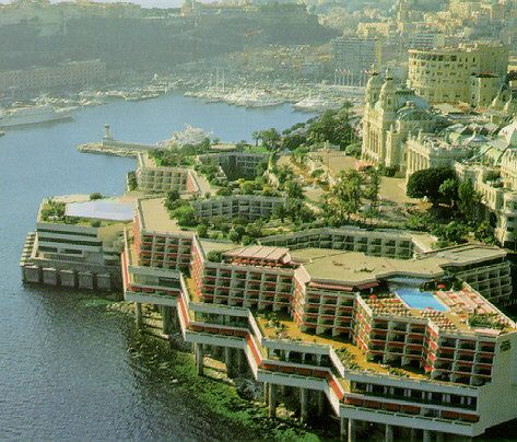 an aerial view of a city with many buildings and boats in the water near it