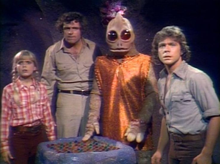 three men standing in front of an alien cake