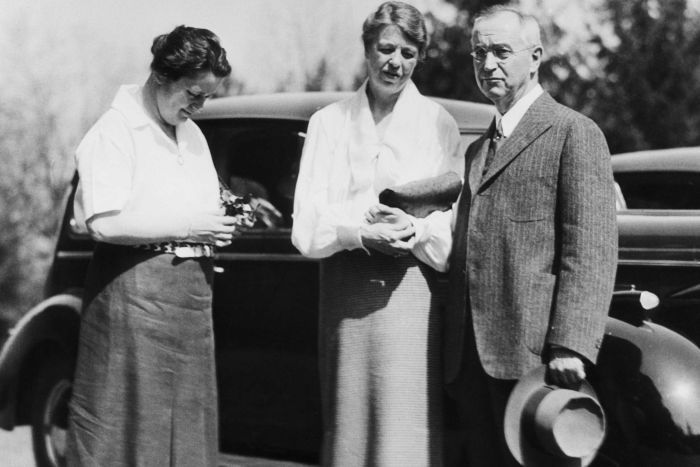 an old black and white photo of three people standing in front of a car