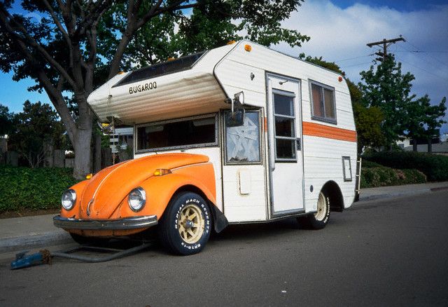 an orange and white camper parked on the side of the road next to trees