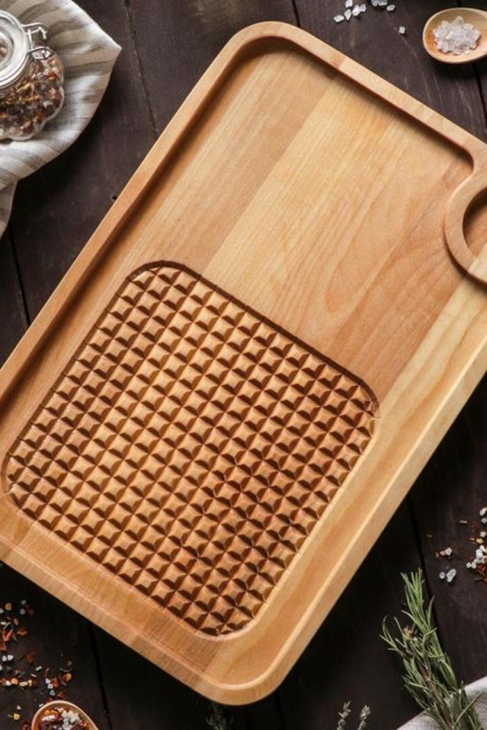 a wooden cutting board sitting on top of a table next to spices and spoons