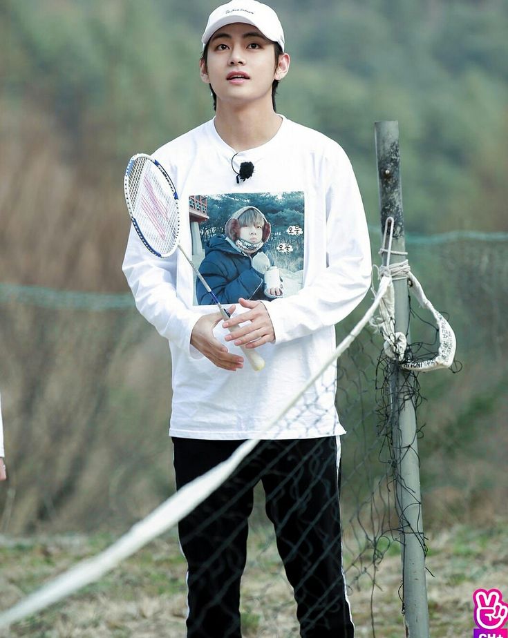 a young man holding a tennis racquet on top of a field