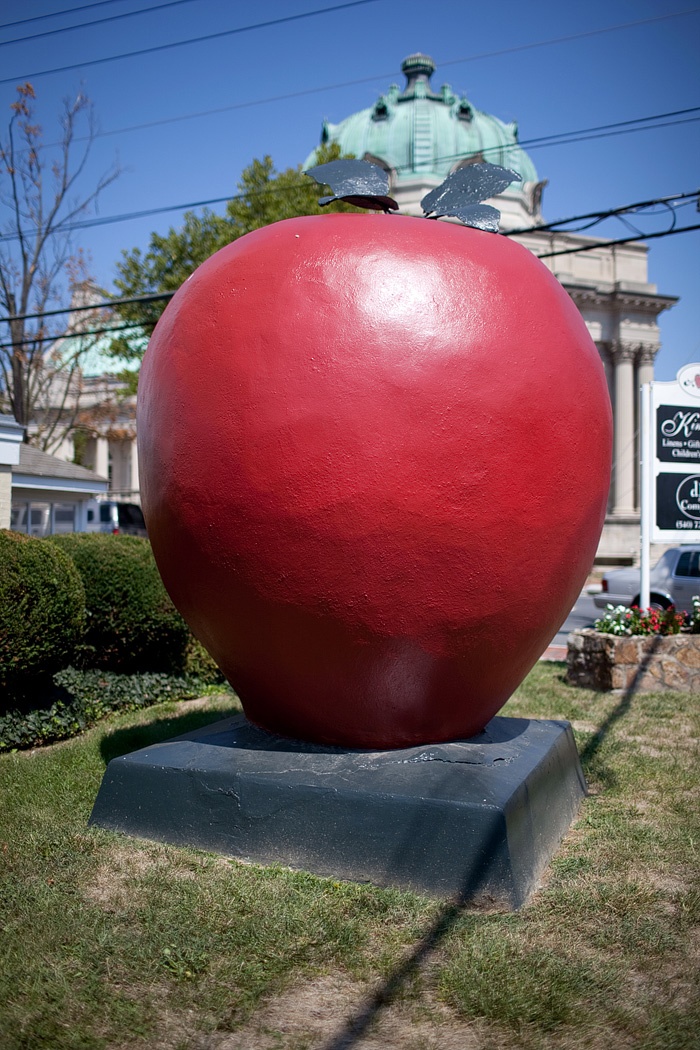 a large red ball sitting on top of a cement block in front of a building