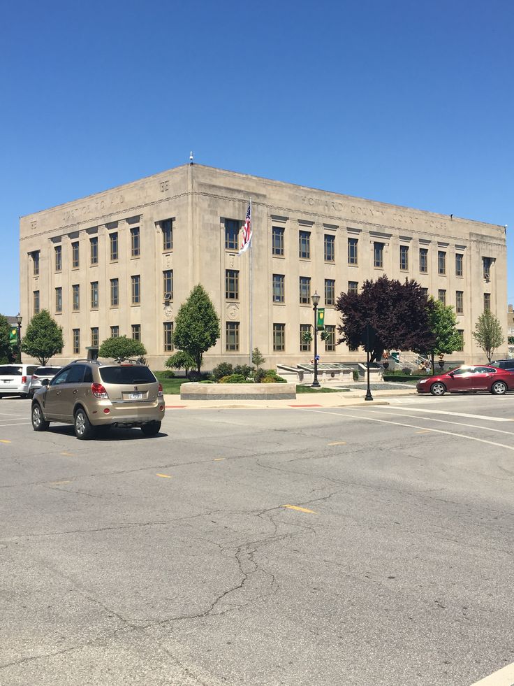 cars are parked in front of an old building with flags on the roof and windows