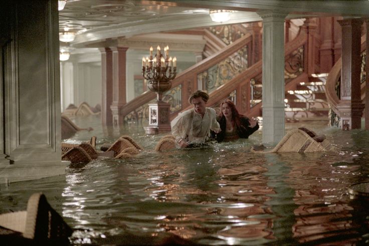 two people are sitting in the middle of a flooded area with stairs and chandeliers