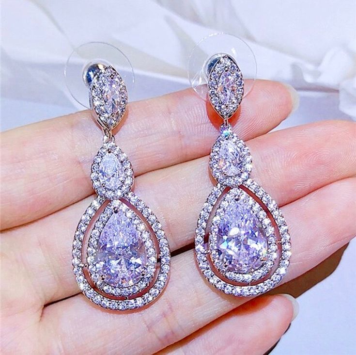 A delightfully unique pair of bridal earrings with an incredible sparkle! Adorned with flawlessly faceted cubic zirconia that capture the light in a dazzling array of sparkles, the earrings are rhodium plated for a bright finish which enhances the intricate detailing and conveys a modern take on old elegance. Overall length of the earring is 1.5" (approx. 4cm). Available in Silver, Rose Gold and Yellow Gold finishes. To make your choice select your preferred finish from the dropdown menu to add Cubic Zirconia Bridal Earrings, Wedding Bridal Jewellery, Stunning Earrings, Silver Rose Gold, Bridal Earrings, Rose Gold Plates, Rhodium Plated, Wedding Jewelry, Diamond Earrings