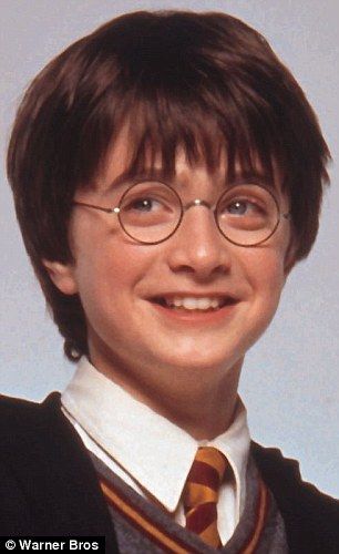 the young harry potter is wearing glasses and a sweater with a striped tie, smiling at the camera