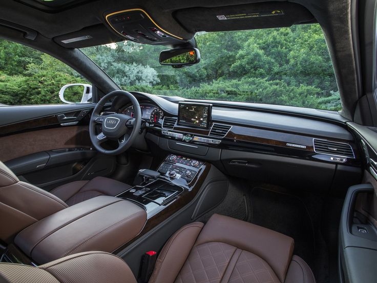 the interior of a car with brown leather seats and dashboard controls, along with trees in the background