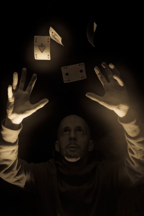 a man holding his hands up in the air with playing cards falling from above him