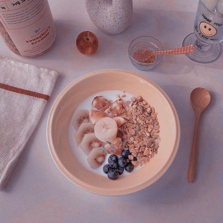 a bowl filled with cereal and fruit next to a bottle of wine