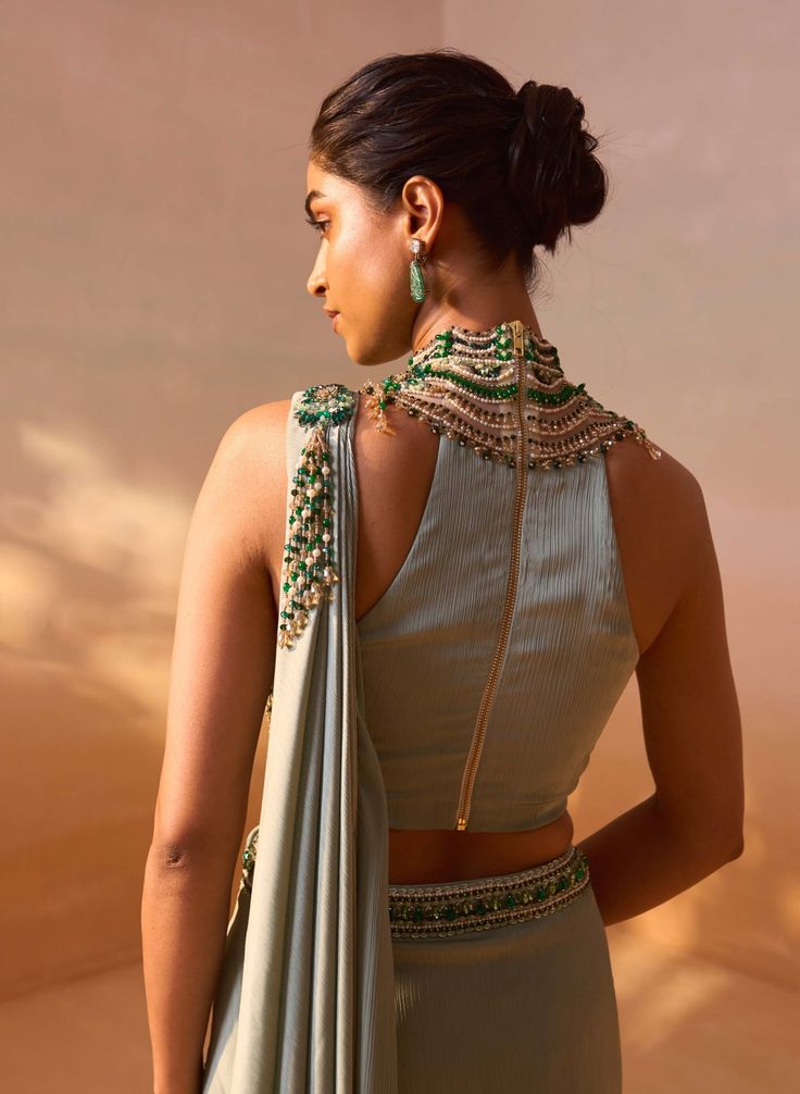 Sage green satin pre-draped sari paired with a jeweled high-neck embroidered blouse, creating a stunning and elegant ensemble. Wedding Draped Cutdana Blouse, Bollywood Style Embellished Draped Blouse, Silk Dupatta Top For Wedding, Silk Top With Dupatta For Wedding, Silk Wedding Top With Dupatta, Wedding Blouse With Resham Embroidery And Draped Shape, Wedding Blouse With Draped Resham Embroidery, Draped Wedding Blouse With Resham Embroidery, Traditional Drape Tops For Eid Reception