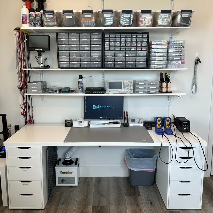 a white desk topped with lots of drawers next to a shelf filled with boxes and containers