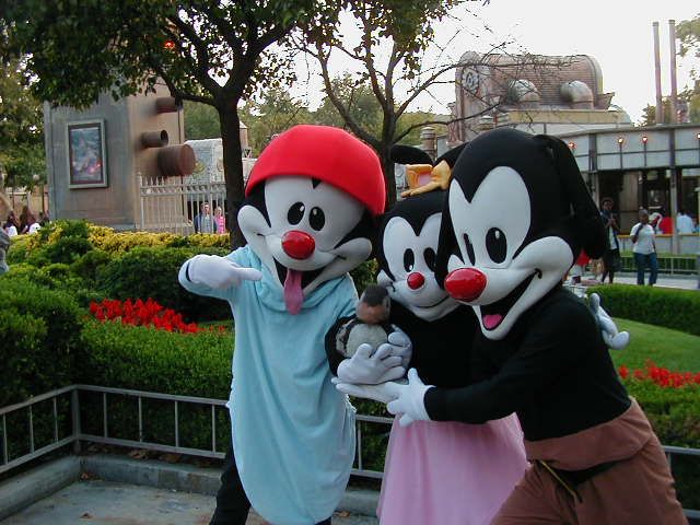 three people dressed in mickey mouse costumes posing for a photo with goofy and minnie mouse