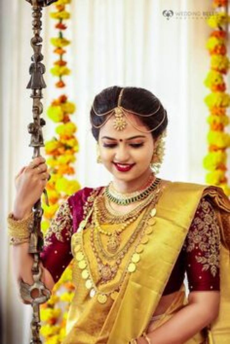 a woman in a yellow and red sari holding a pole with beads on it