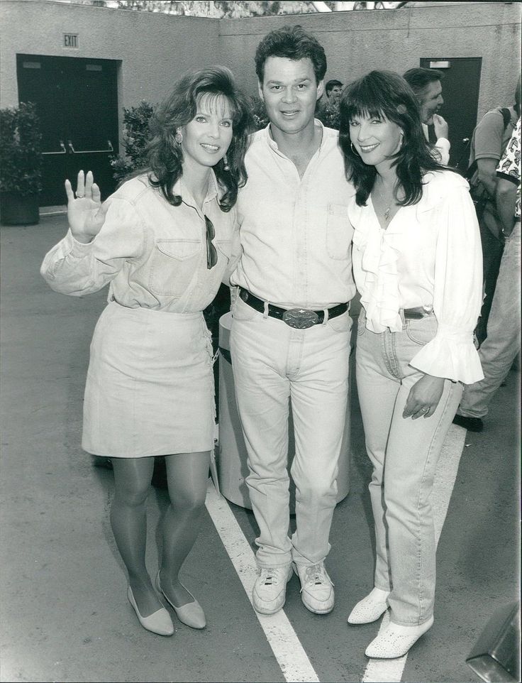 black and white photograph of three people standing in parking lot with one holding up the peace sign