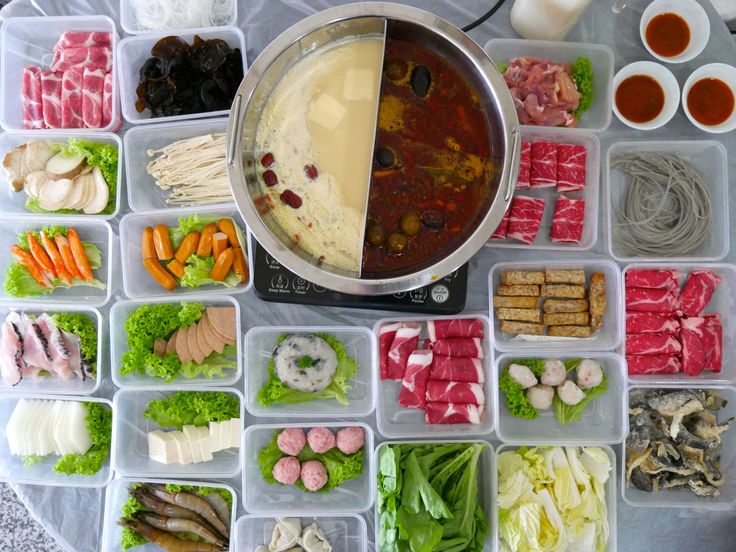 an assortment of food in plastic containers on a table with utensils and sauces