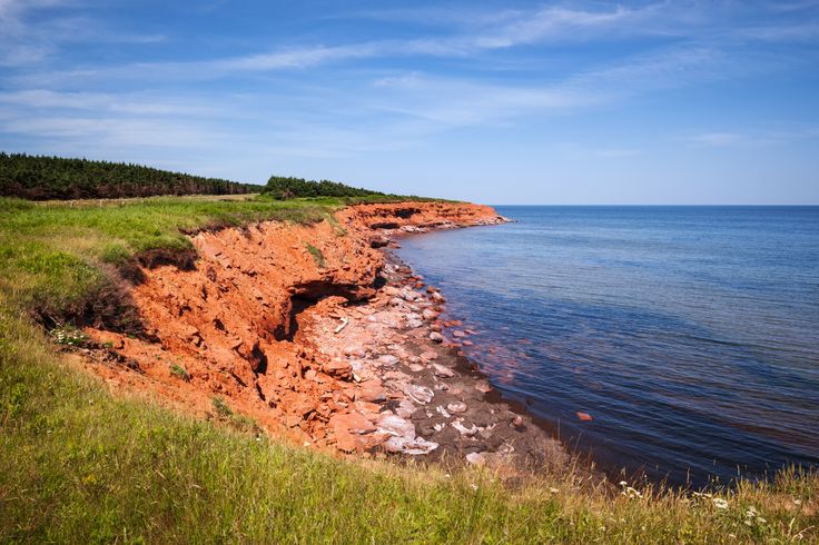 an orange cliff near the ocean on a sunny day