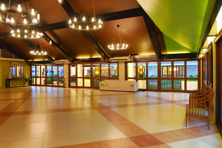 an empty room with chairs and chandeliers in the ceiling, looking out onto the water