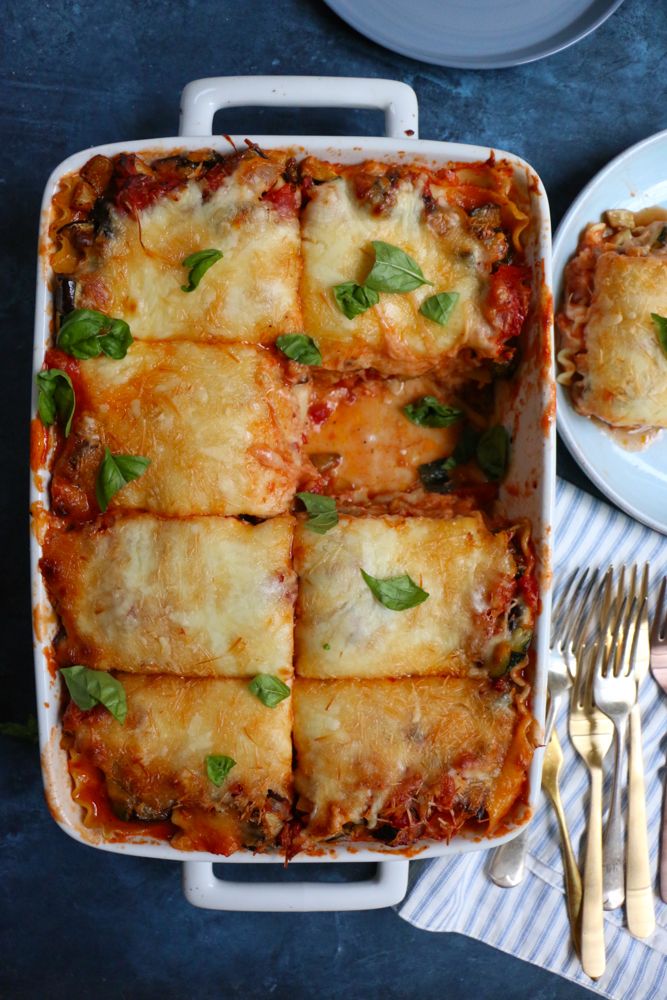 lasagna casserole with meat and cheese in a white dish next to silverware