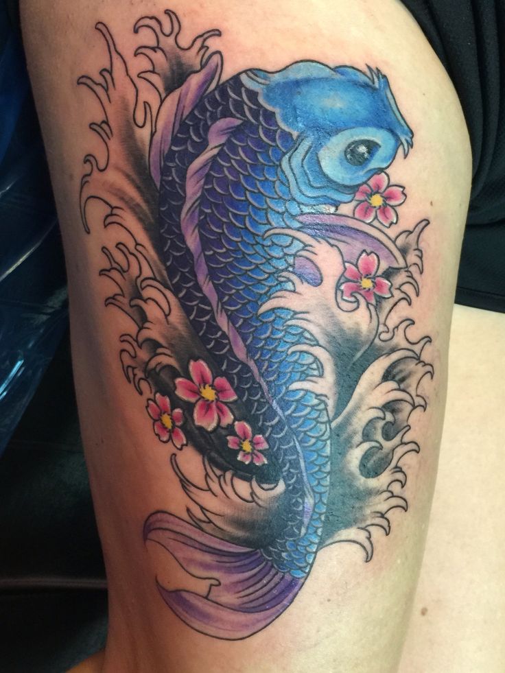 a woman's thigh with a koi fish and flowers tattoo on her leg