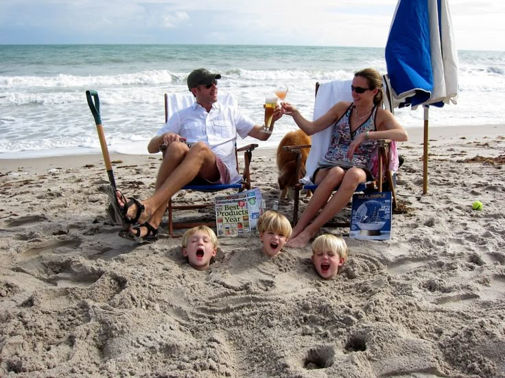 a family sitting on the beach with their dog and two children drinking beer while holding baseball bats