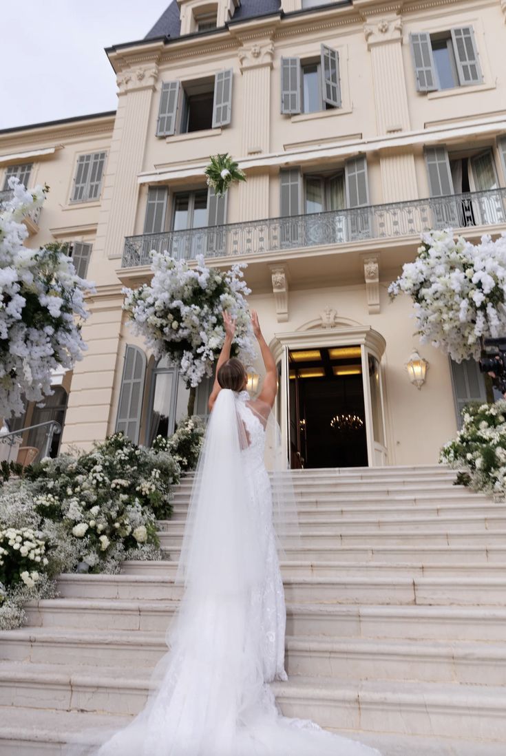 a woman in a wedding dress is standing on the steps outside of a large building