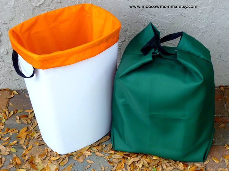 two trash cans sitting next to each other on the ground with leaves all around them